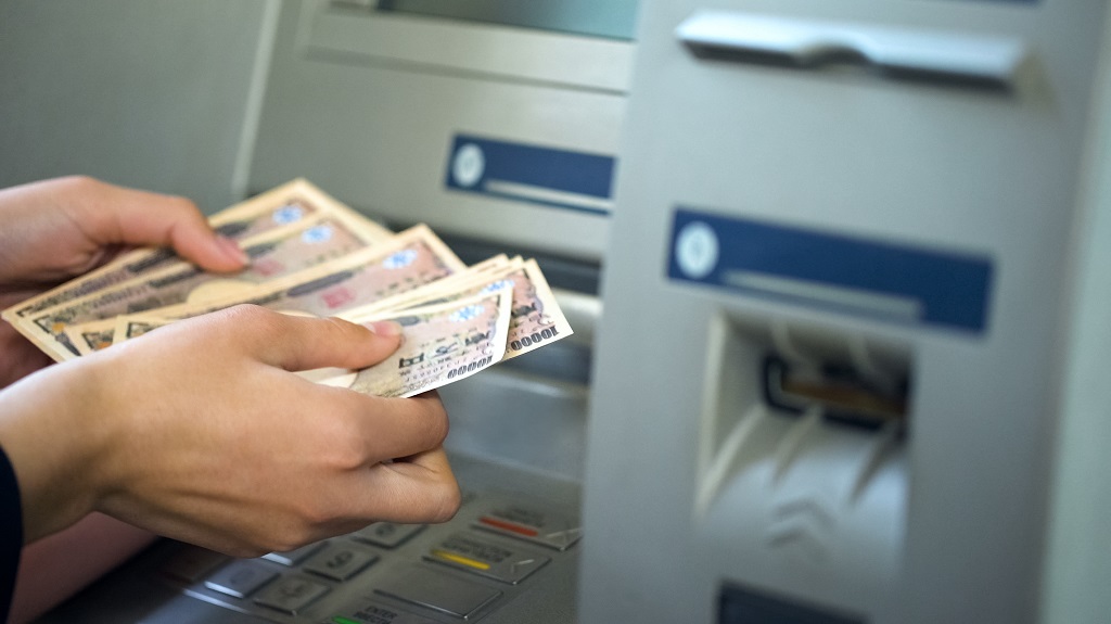Woman counting Japanese Yen withdrawn from ATM, 24 hours service, easy banking